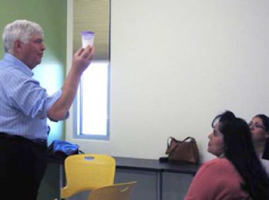 Photo of a person showing a glass of water to a group of people